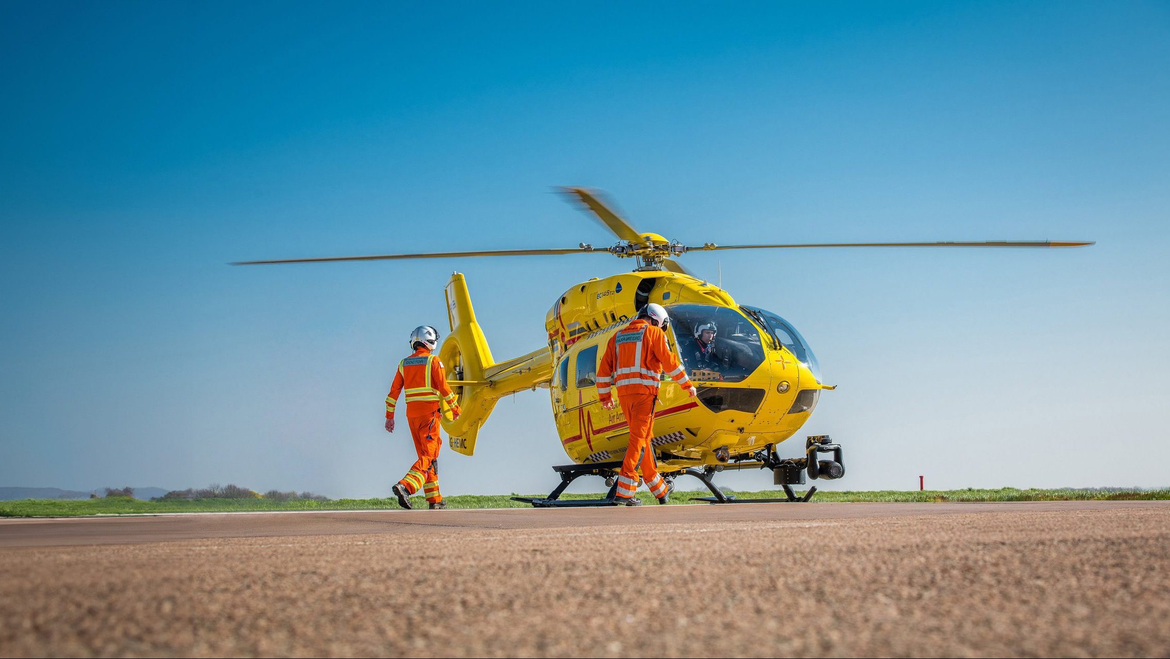 Crew walking to Anglia Two helicopter in sunshine
